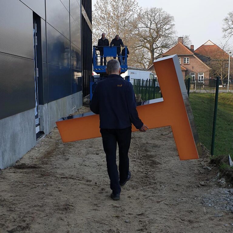 Mann trägt Leuchtbuchstaben zur Montage